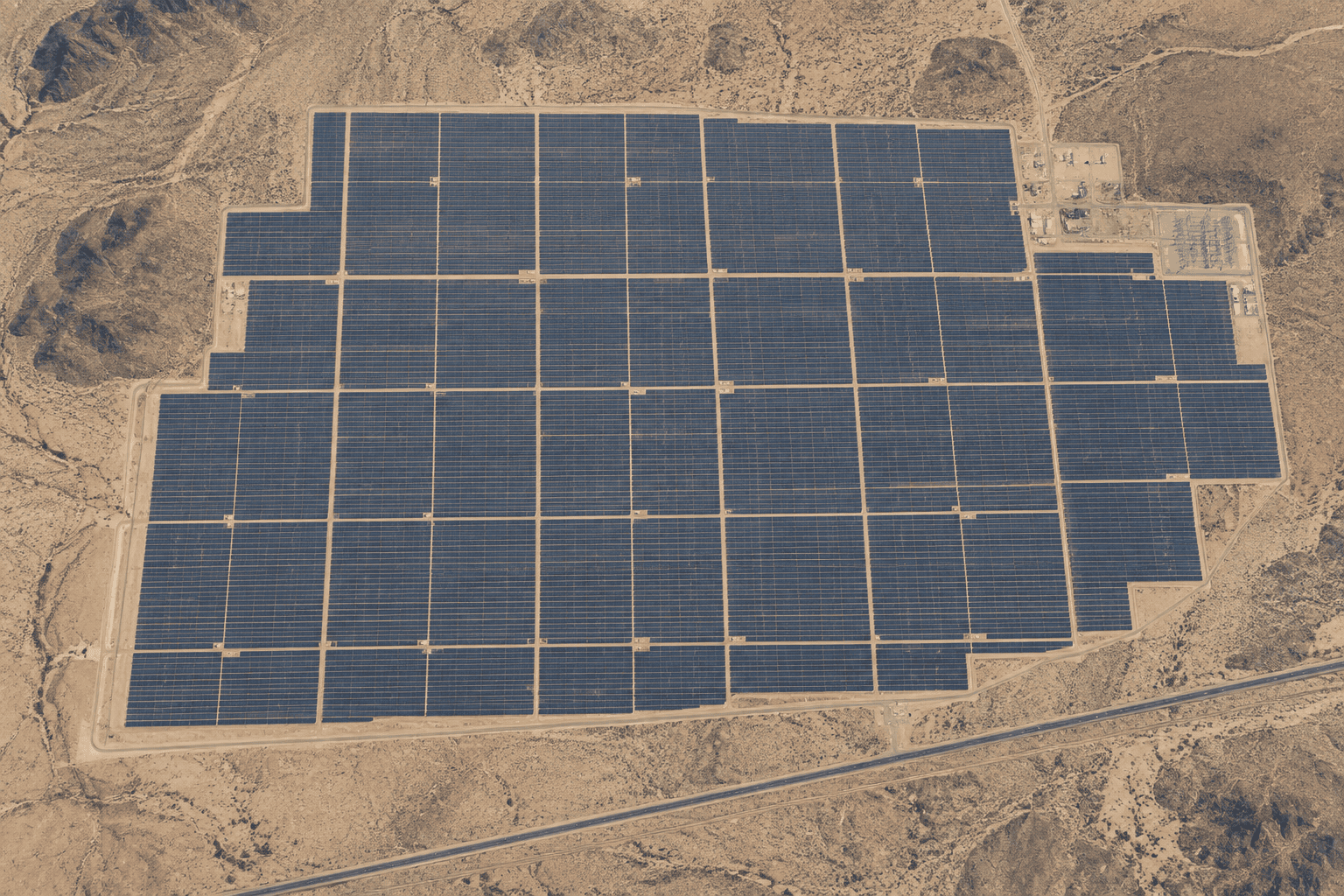 A realistic high-altitude aerial or satellite-style photograph showing a colossal solar photovoltaic installation covering a large portion of a flat Arizona desert valley